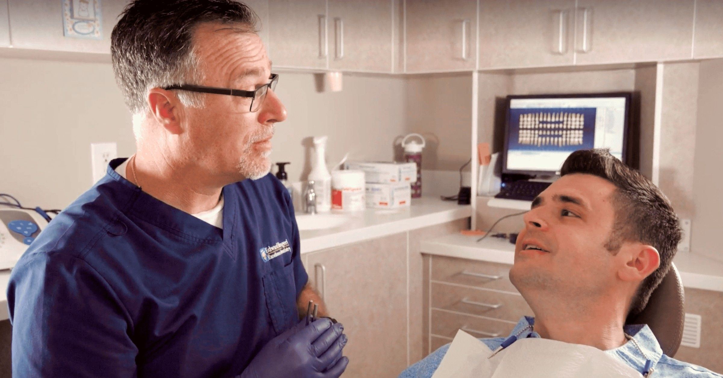 Dr. Ed talking a patient through his x-rays, which are up on the screen behind the chair