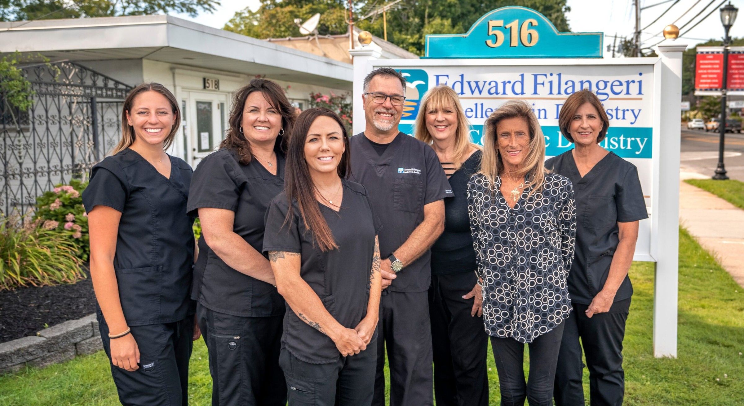 Dr. Ed Filangeri and his six team members standing together by the office sign at 516 Hawkins Avenue
